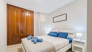 A bedroom with a bed, two nightstands, a wooden wardrobe, and a framed picture on the wall. - Sol Paraiso 2 bedrooms apartment (Adeje)