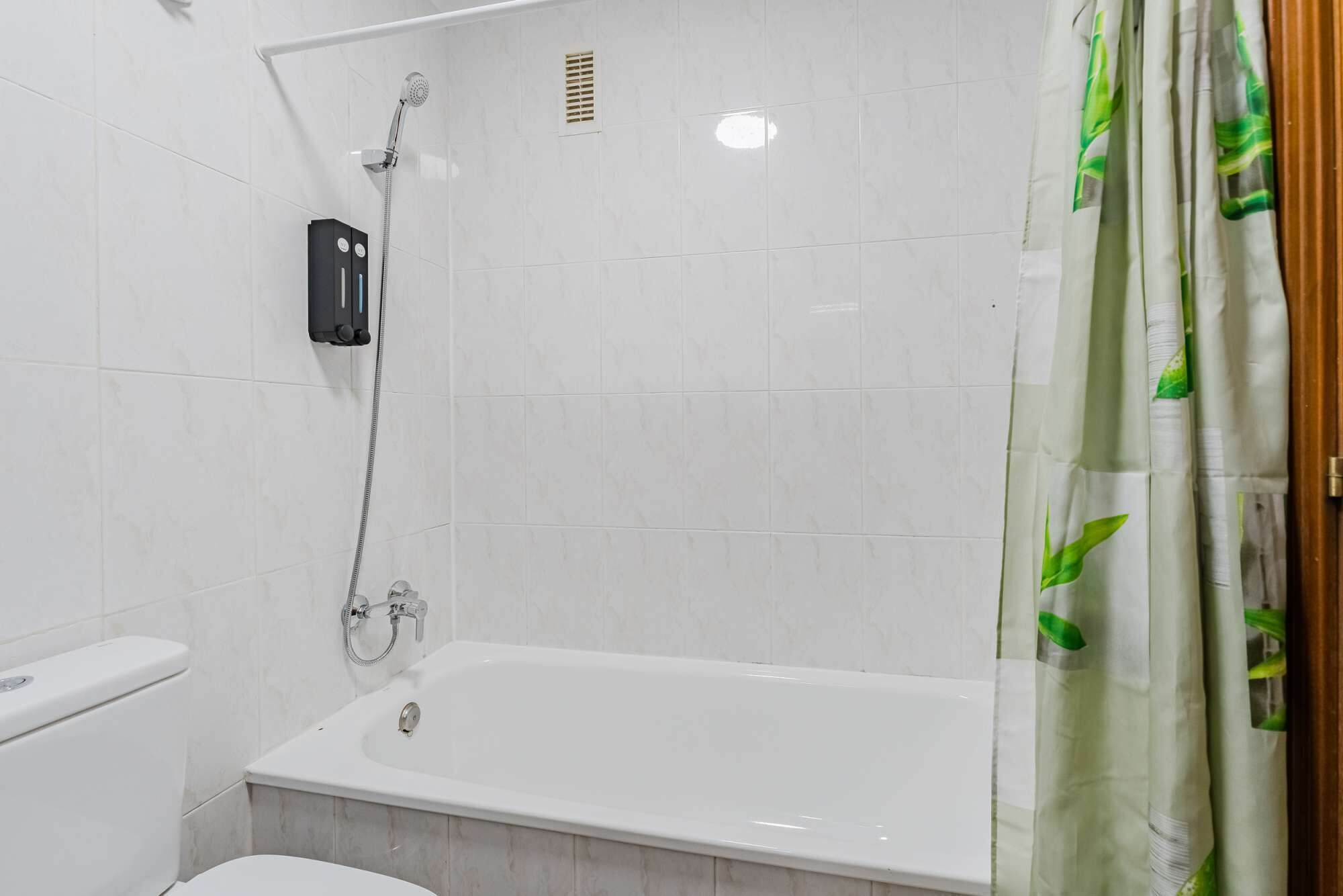 A bathroom with a white bathtub, a toilet, and a showerhead.