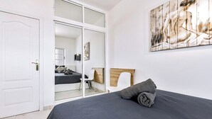 Un dormitorio con cama, un espejo grande y un cuadro en la pared.
