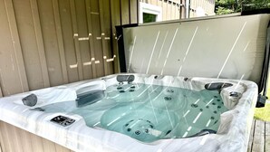 Un bain à remous doté d’un couvercle transparent, de jets intégrés et d’un panneau de commande.