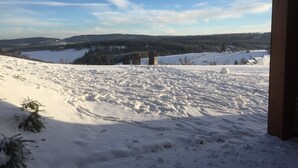 A snowy landscape with a clear sky, a wooden structure, and distant hills. - Apartment in Winterberg / Neuastenberg met uniek uitzicht en tuin (Winterberg)
