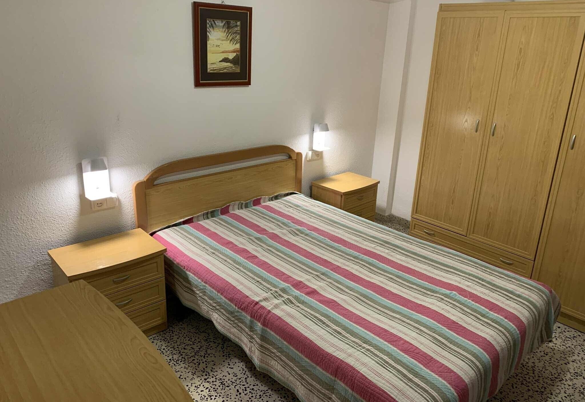 Una camera da letto con un letto, comodini, un armadio e una lampada a parete.