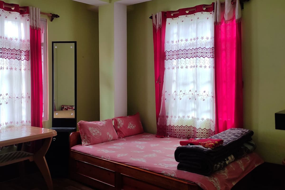 A bedroom with a wooden bed, a desk, and a mirror.