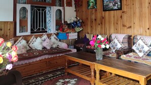 A cozy living room with a wooden sofa, a wooden coffee table, and a patterned rug. - Bhagirath Homestay (Mirik)