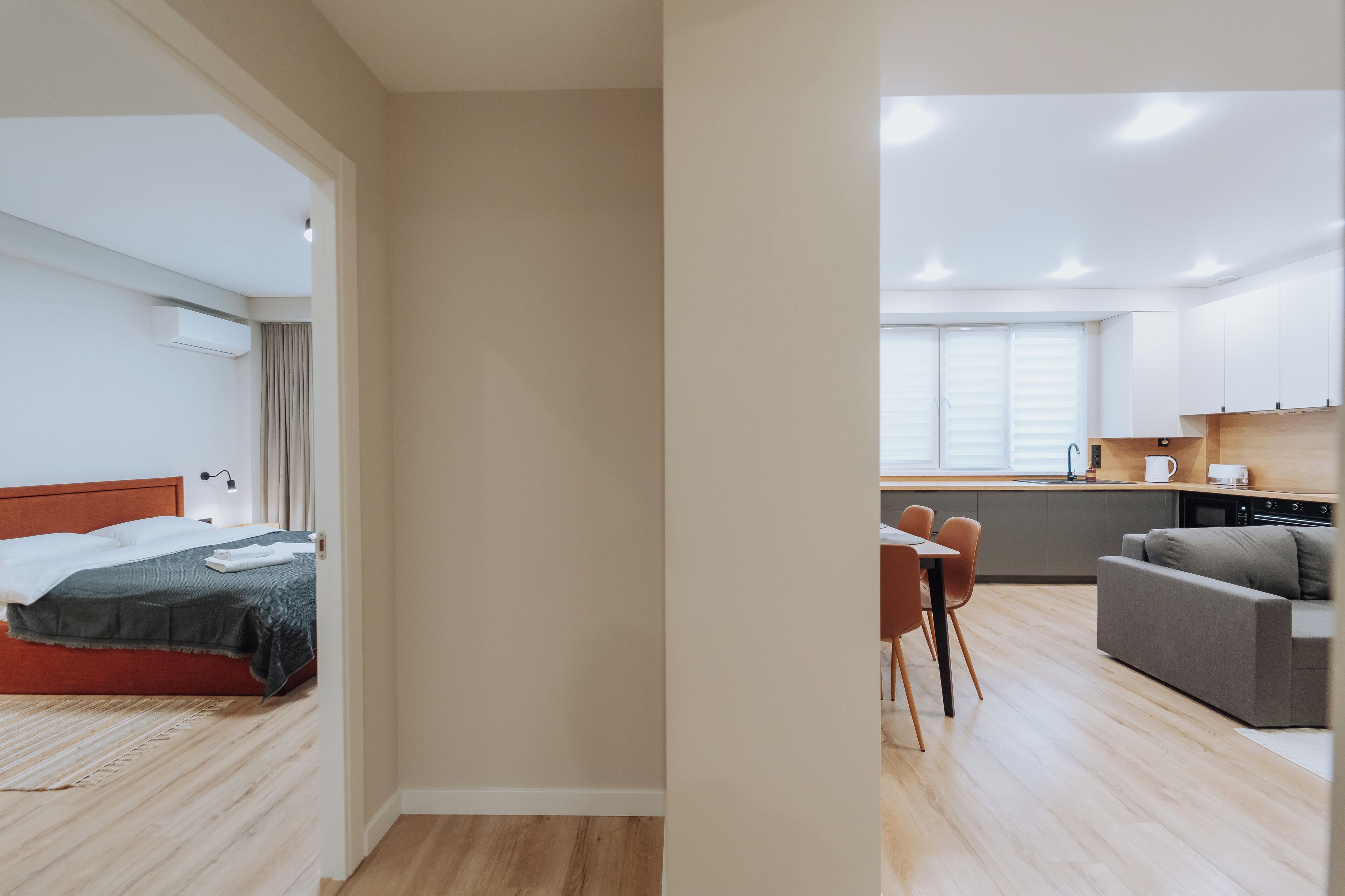 A modern hotel room with a bed, a desk, and a kitchenette.