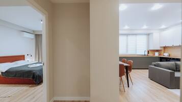 A modern hotel room with a bed, a desk, and a kitchenette.