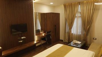 A hotel room with a bed, a desk, a chair, a TV, and a wardrobe.