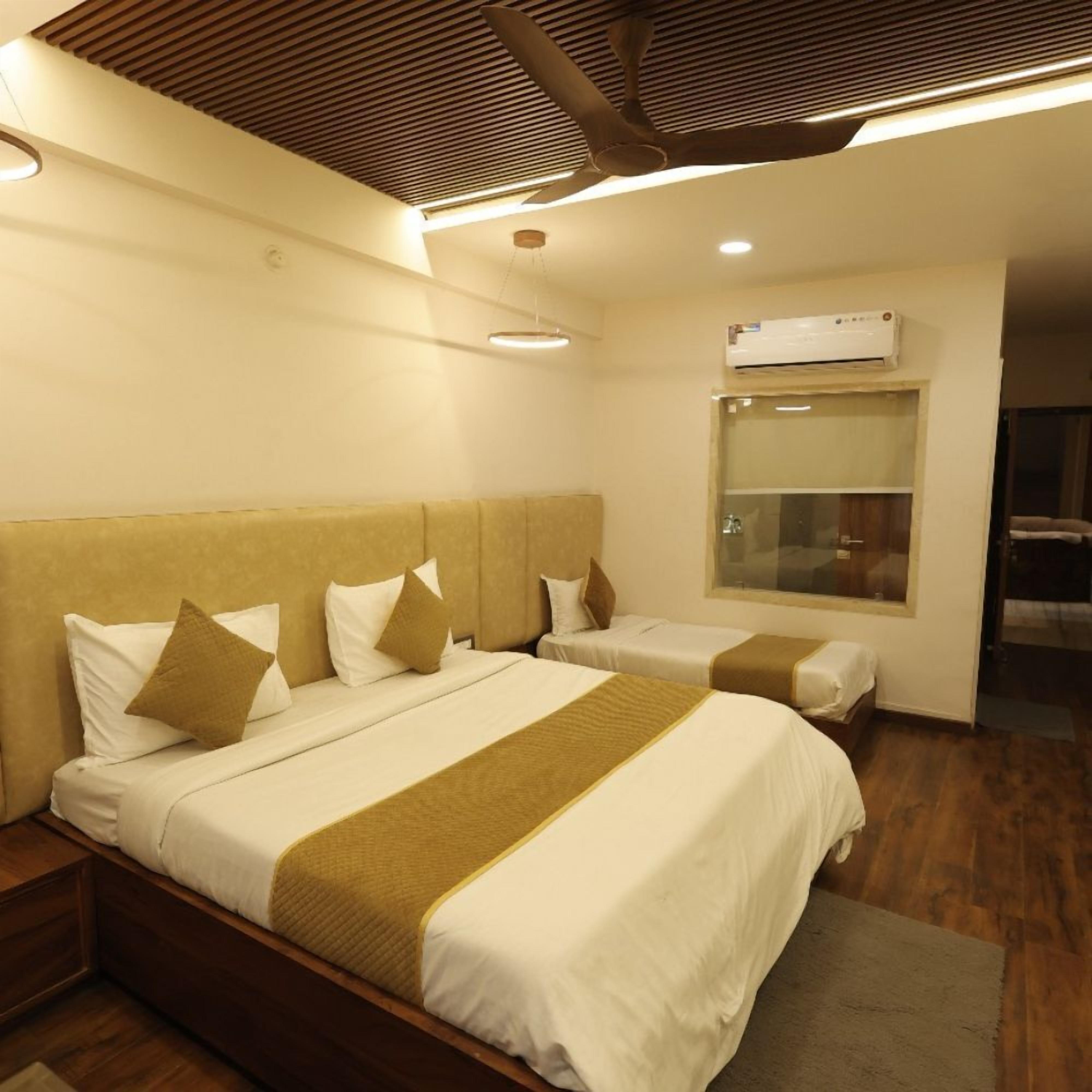 A hotel room with two beds, a wooden headboard, a large window, and an air conditioning unit.