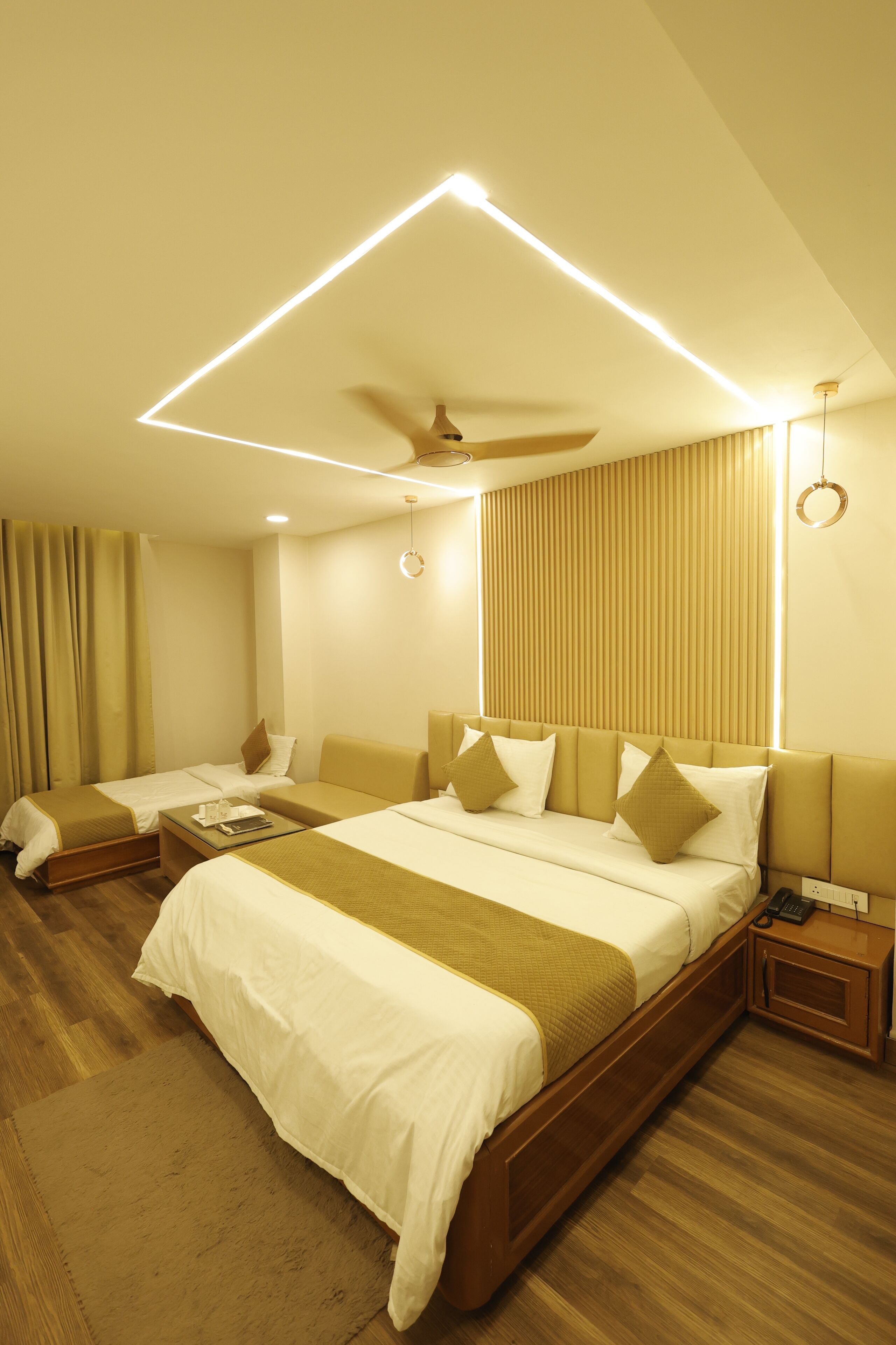 A hotel room with a bed, a bedside table, a lamp, and a window with blinds.
