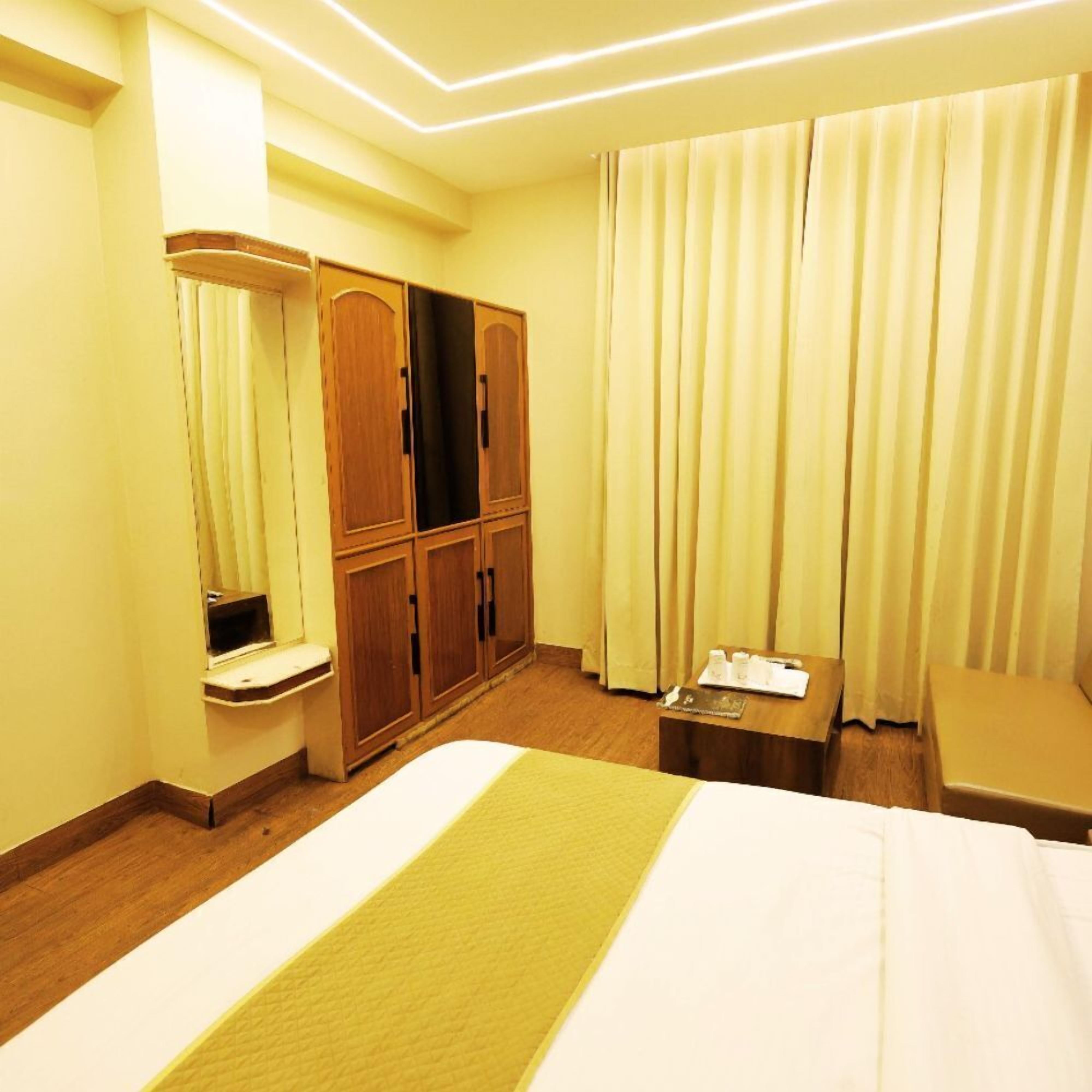 A hotel room with a bed, a wardrobe, a desk, and a window with curtains.