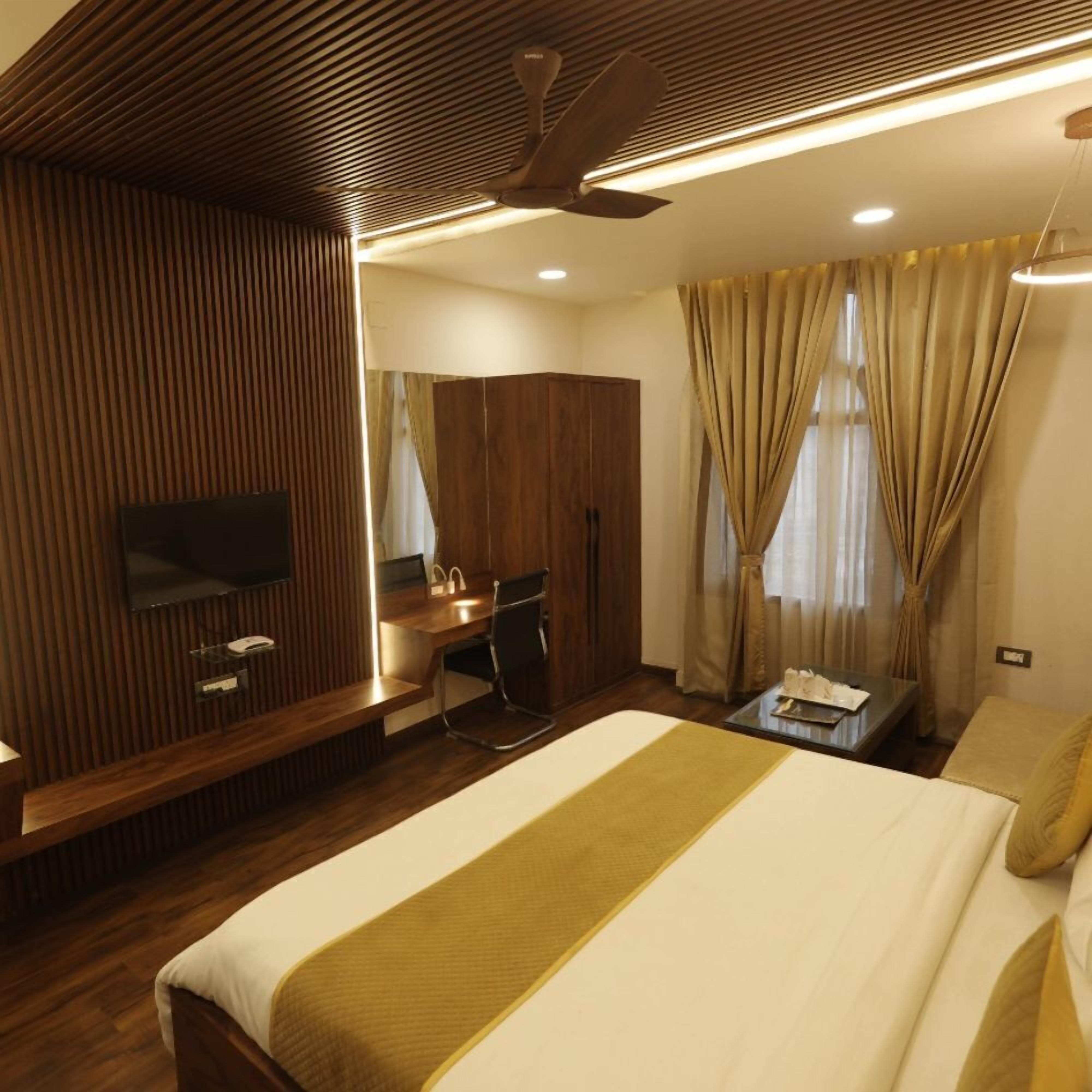 Ein Hotelzimmer mit Bett, Schreibtisch, Sessel, Fernseher und Kleiderschrank.