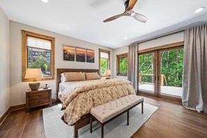 A bedroom with a large bed, a ceiling fan, and a view of the outdoors through large windows. - Sweet Bearadise-Eagles Nest - dogs ok, outdoor fireplace (Banner Elk)