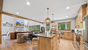 A spacious kitchen with wooden cabinets, a large island, and a dining area with a sofa and chairs.