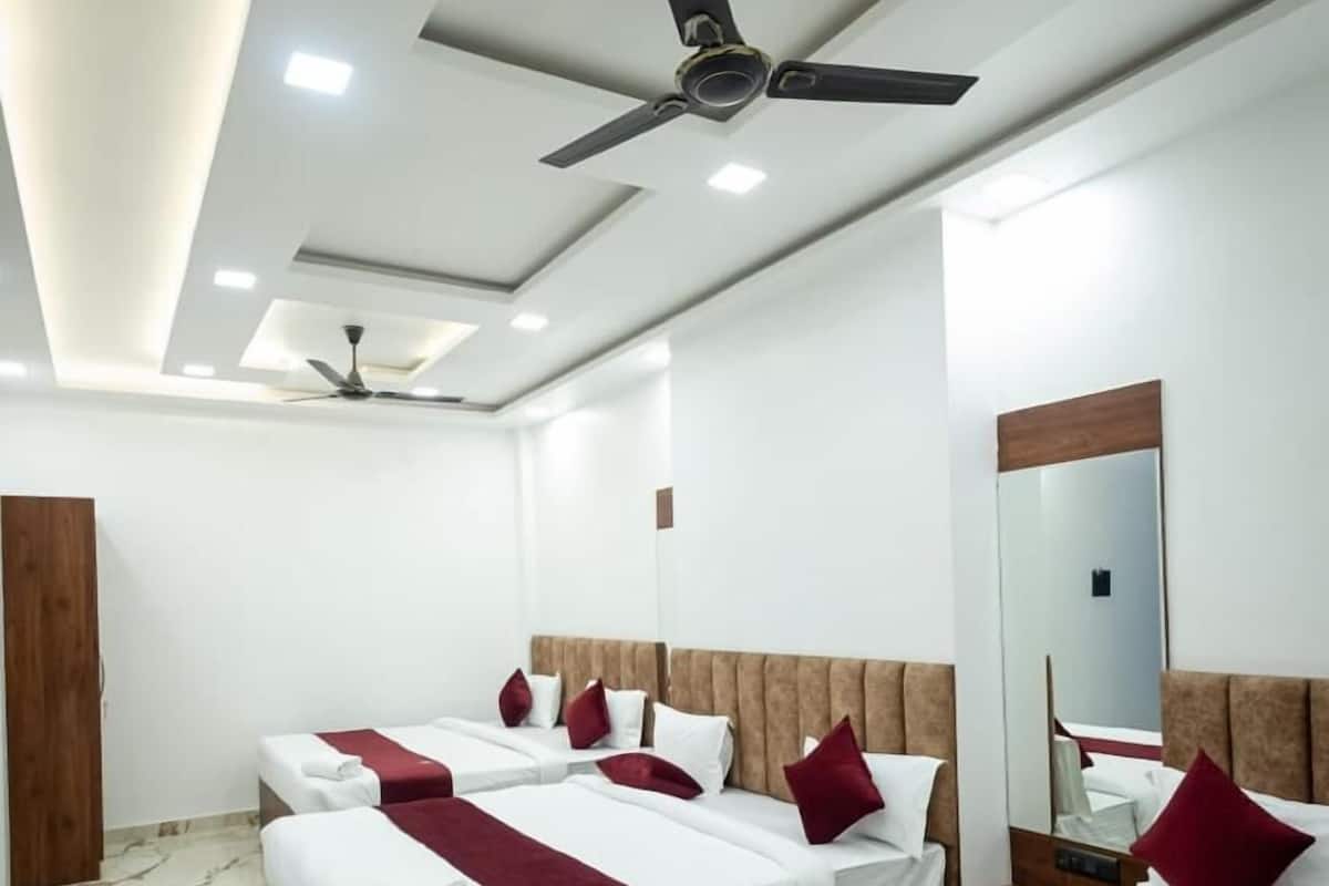 A hotel room with four beds, marble flooring, ceiling fans, and a large mirror.
