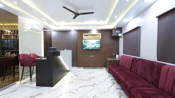 A modern lobby with a reception desk, seating area, and a large TV screen. - The Satnam Inn (Varanasi)