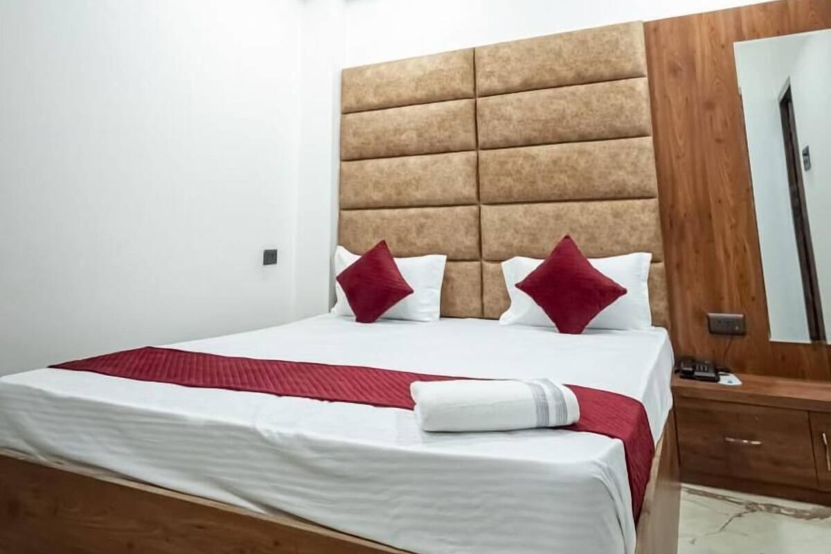 A hotel room with a wooden bed, a ceiling fan, and a large mirror on the wall.