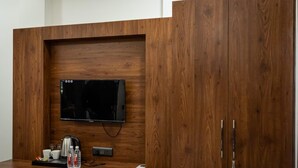 A wooden wall unit with a flat-screen TV, a coffee maker, cups, and bottled water. - The Satnam Inn (Varanasi)