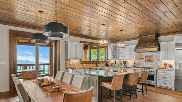 A spacious kitchen with a large island, wooden ceiling, and a view of mountains.