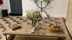 Una taula de cafeteria de fusta, un vas amb flors, un bol de fruita i un tauler d'escacs.