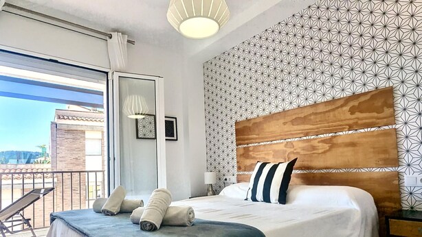 Un dormitorio con una cama grande, cabecera de madera y pared con diseño.