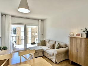 A modern living room with a sofa, a dining table, a lamp, and a cabinet.