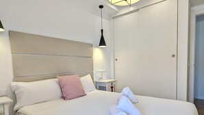 A hotel room with a large bed, a bedside table, a lamp, and a wardrobe.