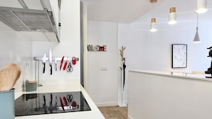 A modern kitchen with a black countertop, hanging knives, and pendant lights.