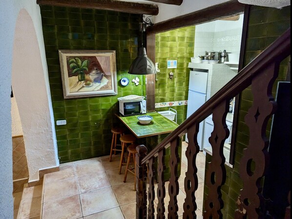 A kitchen with a green tiled backsplash, a microwave, a sink, and a dining area with stools. - Historic House in Tossa de Mar - Pets Welcome, Sleeps 7 (Tossa de Mar)