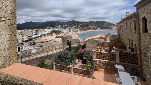 A coastal town with stone buildings, a beach, and a view of the sea.