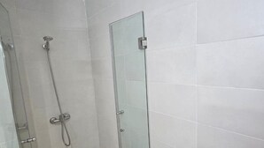 A bathroom with a glass shower enclosure and a glass door.