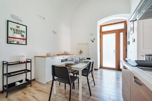A modern kitchen with a white countertop, black chairs, and a wooden dining table. - Giosue' Apartment Near Bari (Adelfia)