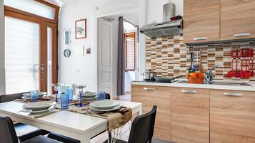 Uma cozinha moderna com armários de madeira, uma mesa de jantar posta para quatro pessoas e vista para a área de jantar adjacente.