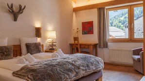 A bedroom with a bed, a desk, a chair, a lamp, a deer head decoration, a radiator, and a window with a view of the outdoors. - Lovely apartment in villa for 15 guests with WIFI, hot tub and terrace (Vercorin)