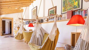 A room with wooden floors, hanging hammocks, a red lamp, and bookshelves with various books. - Lovely apartment in villa for 15 guests with WIFI, hot tub and terrace (Vercorin)