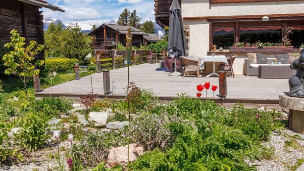 A wooden lodge with a patio area featuring outdoor seating and a statue. - Lovely apartment in villa for 15 guests with WIFI, hot tub and terrace (Vercorin)
