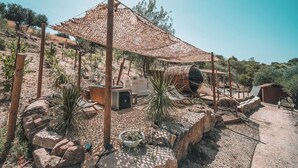 Un espacio exterior rústico con un porche de madera, paredes de piedra y plantas en macetas.