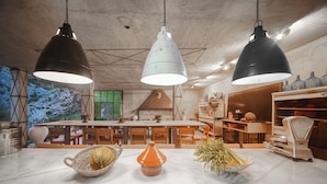 Una cocina rústica con una gran mesa de madera, lámparas colgantes y una balanza.