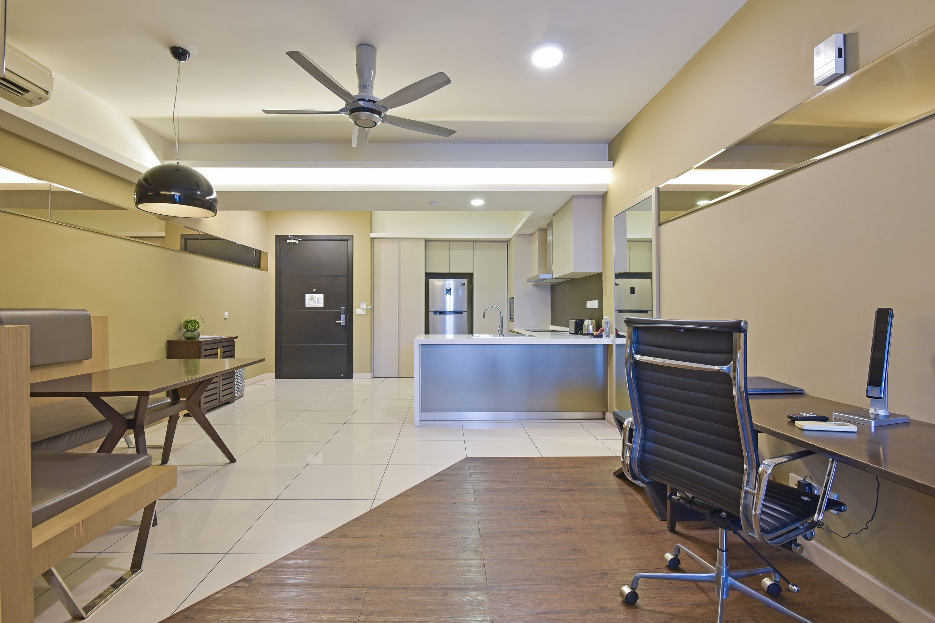 A modern office space with a desk, chair, and kitchenette.