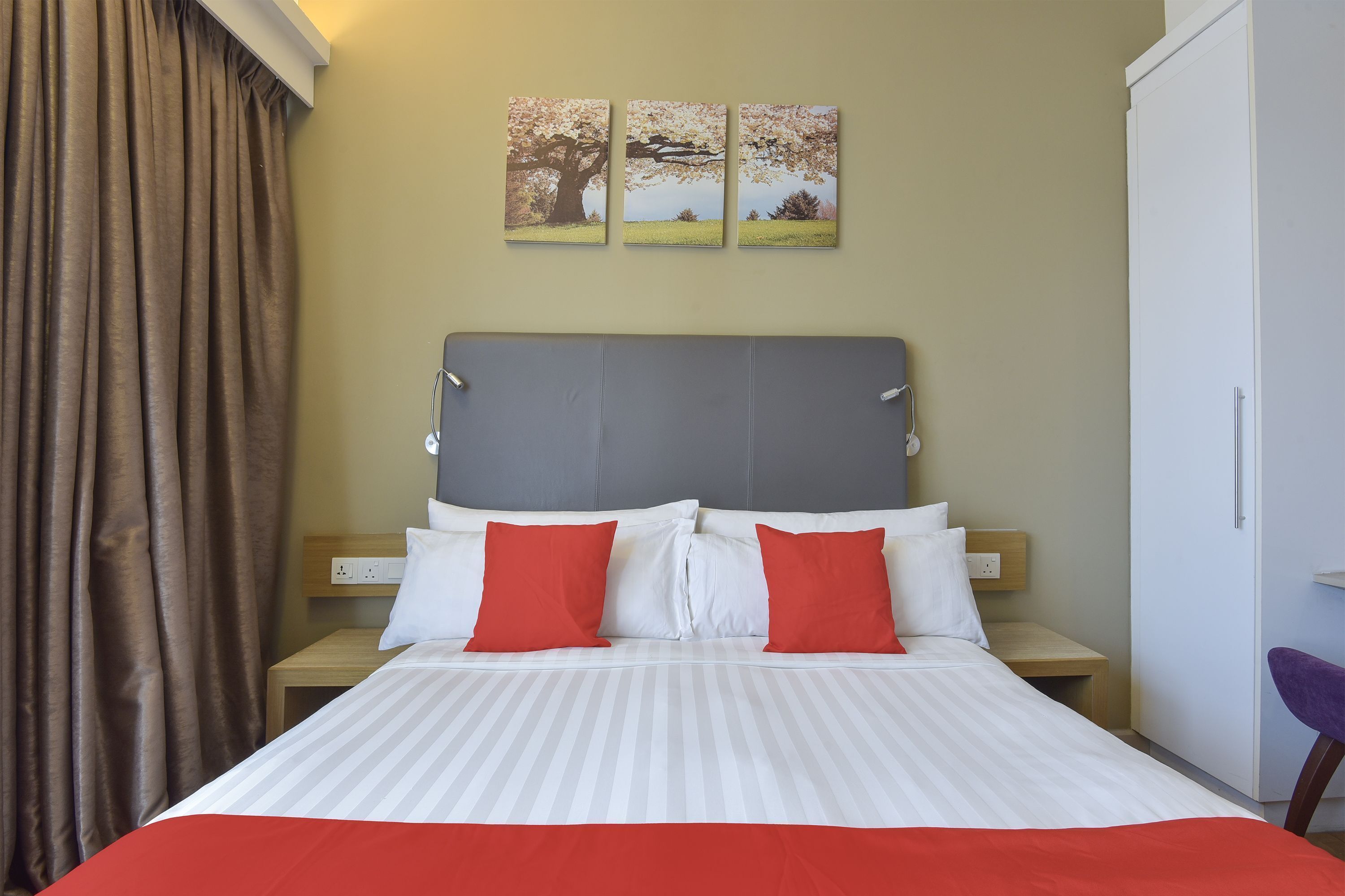 Ein Hotelzimmer mit Bett, Kopfteil, Nachttisch, Sessel und Kleiderschrank.