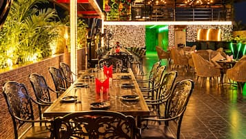 Un área de comedor al aire libre con una mesa larga, sillas y una pared decorativa.