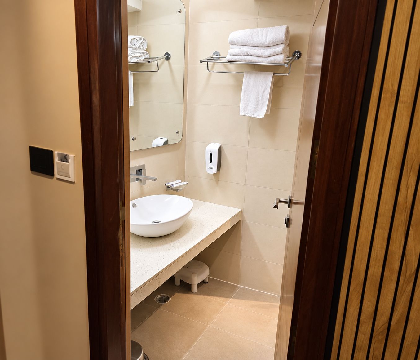 A bathroom with a white sink, a mirror, a towel rack, and a soap dispenser.