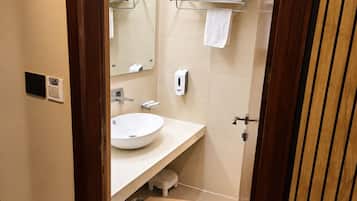 A bathroom with a white sink, a mirror, a towel rack, and a soap dispenser.