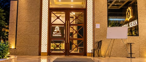 Entrada de un hotel con un cartel que dice 'Royal Serena' y un logotipo sobre la puerta.