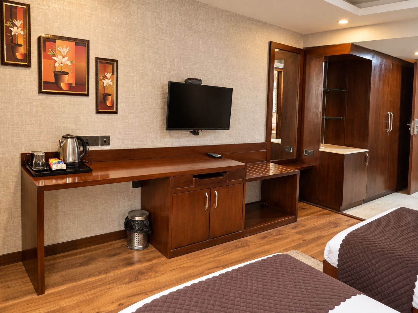 Habitación de hotel con escritorio de madera, televisión, armario y dos camas.