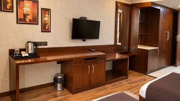 Habitación de hotel con escritorio de madera, televisión, armario y dos camas.