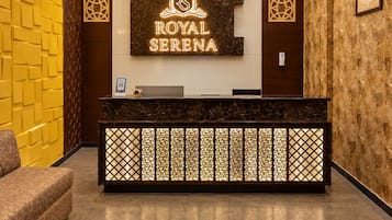 Una mesa de recepción con un cartel que dice 'ROYAL SERENA' y una obra de arte enmarcada con pájaros en la pared.