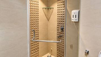 Une douche moderne dotée d’une porte en verre, d’une barre d’appui et d’un distributeur de savon.