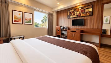 Una habitación de hotel con una cama grande, un escritorio y un televisor de pantalla plana, y obras de arte en las paredes.