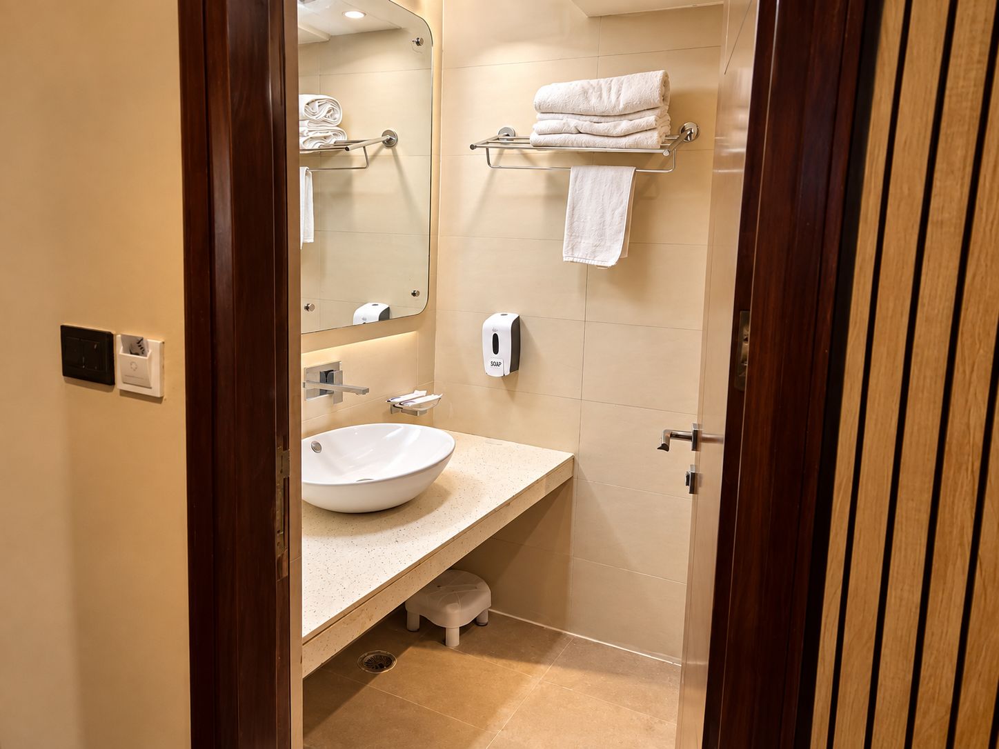 A bathroom with a sink, towel rack, and a soap dispenser.
