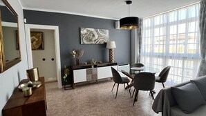 En moderne stue med sofa, spisebord, stole og et køkkenområde med skab og pynt.